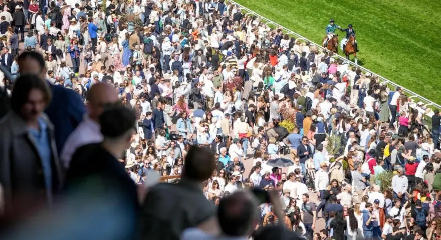 Foule nombreuse sur un hippodrome en France, spectateurs massés pour une course de chevaux.