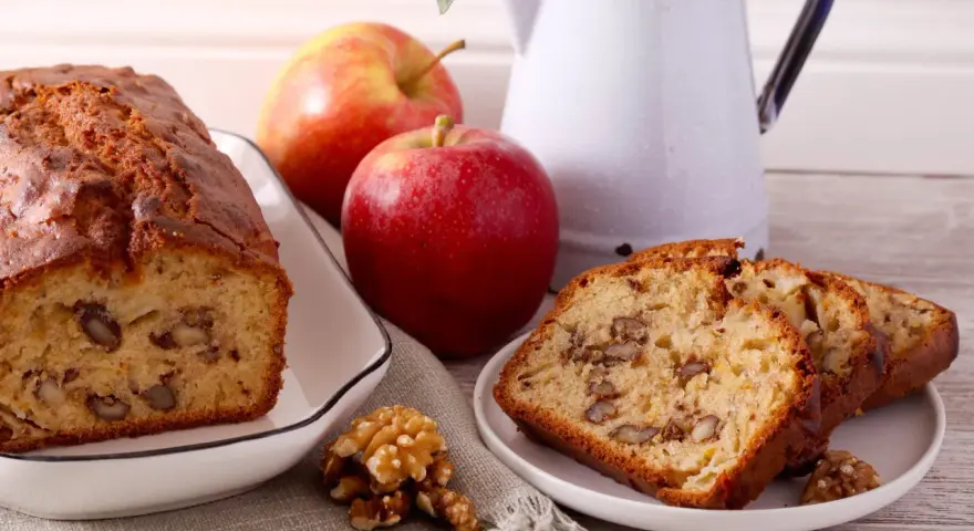 Un délicieux gâteau aux pommes et noix de grand-mère, avec des tranches présentées sur une assiette.