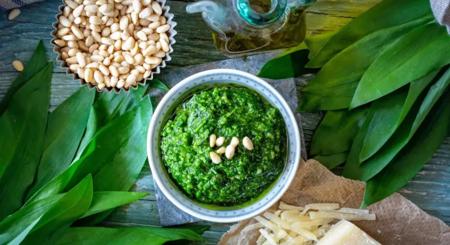 Pesto z czosnku niedźwiedziego, orzechów pinii i oliwy. Obok kawałek sera, który może być alternatywą, jaki ser do pesto zamiast parmezanu?