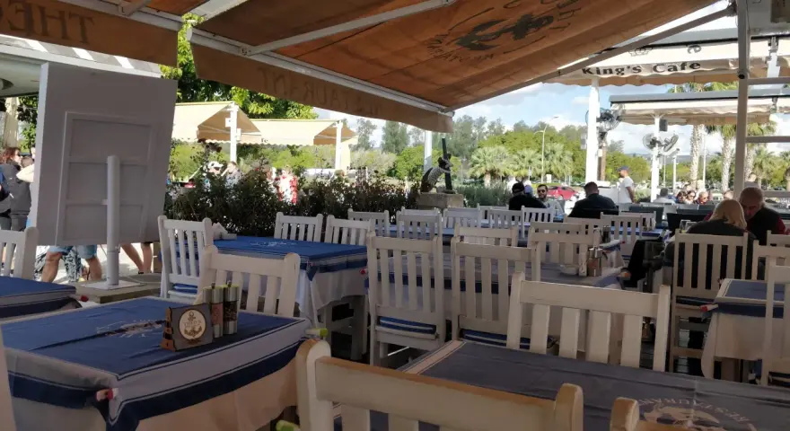 Uroczy ogródek restauracyjny w Larnace z niebiesko-białymi obrusami. Idealne miejsce, by dowiedzieć się, co i gdzie zjeść w Larnace.