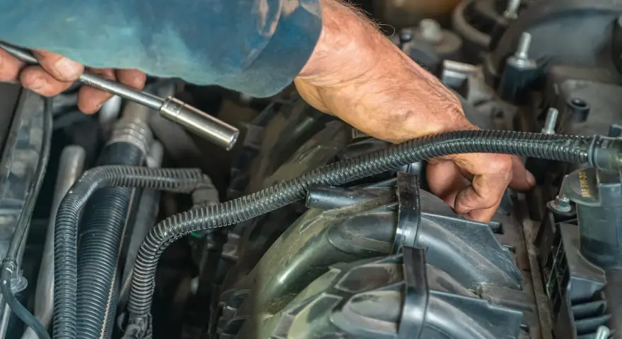 Mechanik naprawia silnik, sprawdzając uszkodzony zawór zwrotny paliwa. Objawy mogą być różne, od problemów z rozruchem po nierówną pracę silnika.