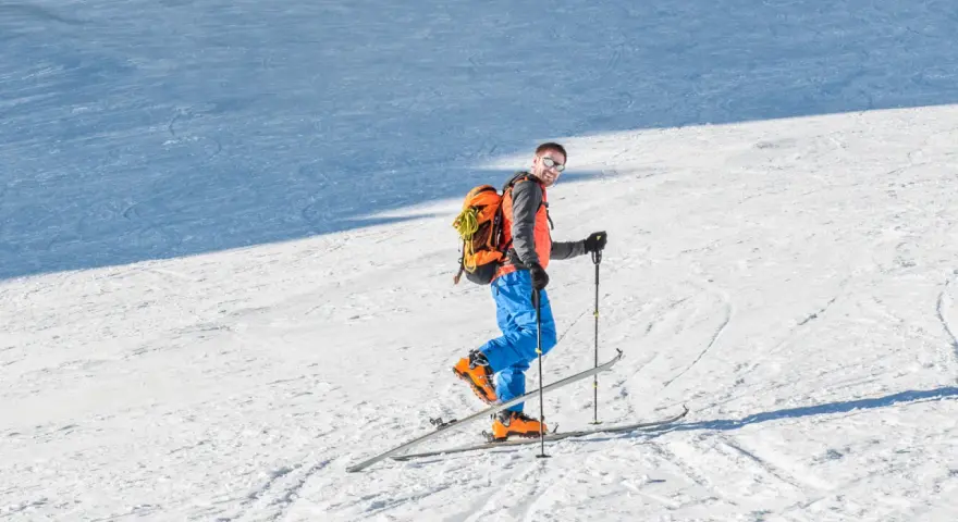 Mężczyzna na nartach z plecakiem, gotowy na skitury. Co to za przygoda?