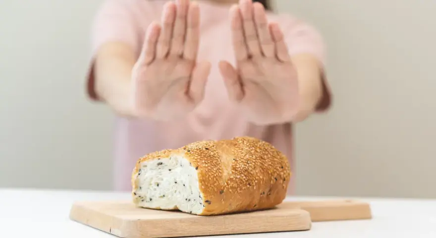 Osoba odrzuca chleb, sygnalizując uczulenie na gluten i laktozę objawy.