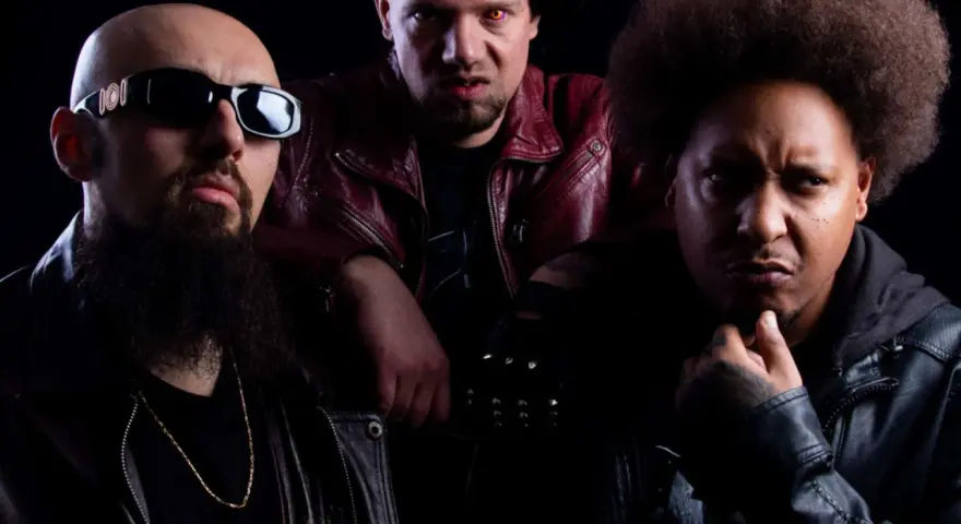 Trois hommes au look sombre, dont un avec des lunettes de soleil et une barbe, un autre avec des yeux jaunes et une veste rouge, et le troisième avec une afro. Un trio dope dod.