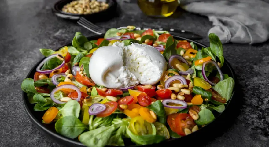 Frischer Salat mit Burrata, Tomaten, Zwiebeln und Pinienkernen. Perfekt für eine leichte Mahlzeit, auch in der Schwangerschaft.