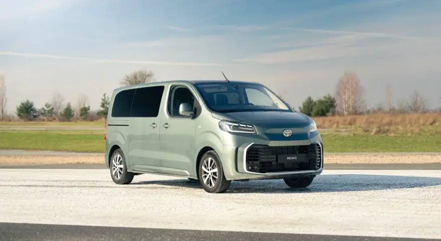 Nowy, zielony minivan Toyota Proace na tle nieba i pól. Idealny na rodzinne wycieczki.