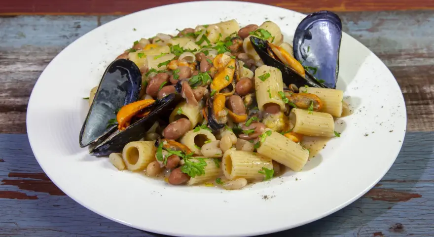 Piatto di pasta fagioli e cozze, con rigatoni, fagioli borlotti e cannellini, cozze nere e prezzemolo tritato.