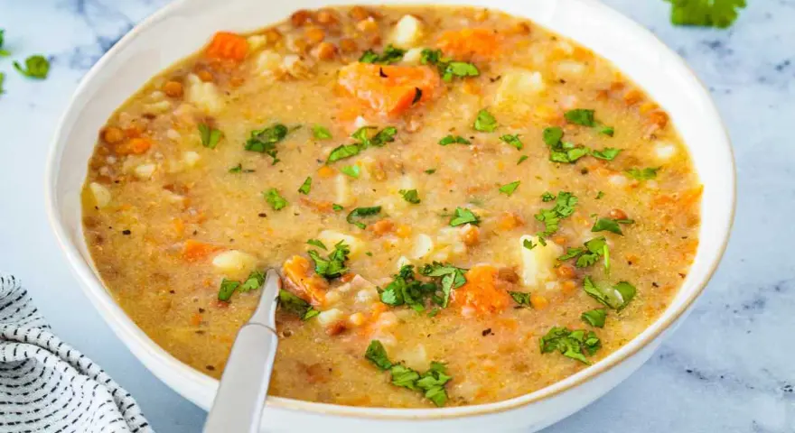 Un tazón de sopa de lentejas casera con zanahorias y patatas, perfecto para aprender como hacer lentejas.
