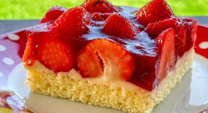 Ein saftiges Stück Erdbeerkuchen vom Blech, belegt mit frischen Erdbeeren und Tortenguss.