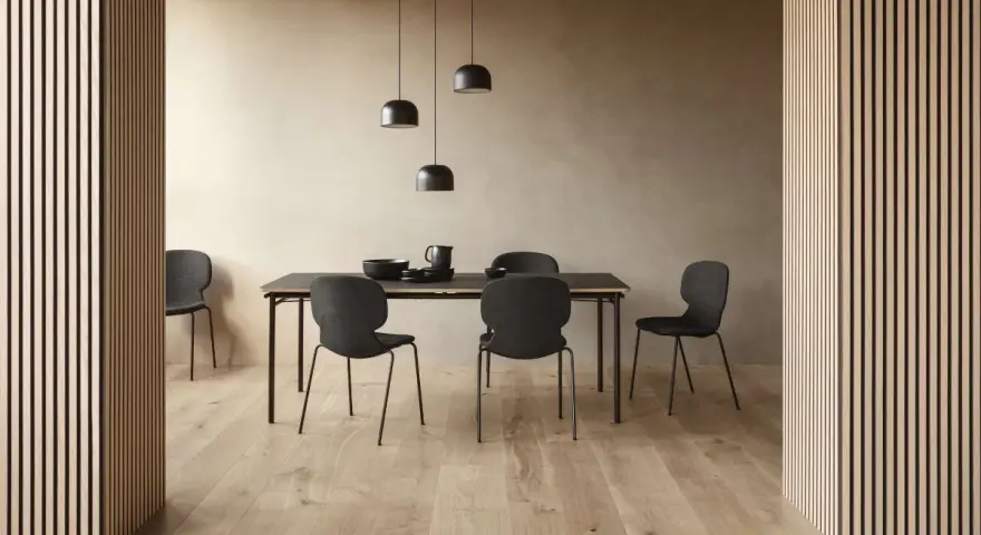 Jadalnia w stylu soft minimalism: czarne krzesła i stół na tle beżowej ściany, oświetlone lampami.