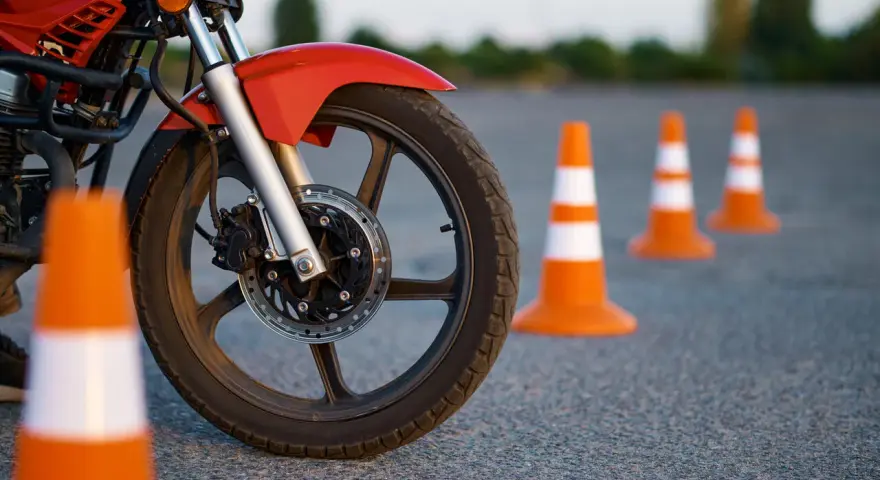 Czerwony motocykl i pomarańczowe pachołki na placu manewrowym. Przygotowanie do egzaminu na kategorie prawa jazdy na motor.