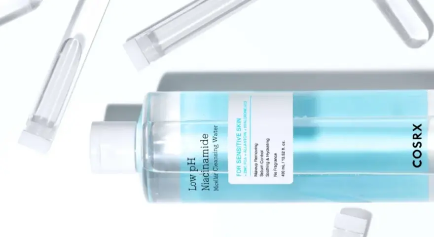 En flaska COSRX Low pH Niacinamide Micellar Cleansing Water, en mild sminkborttagning olja för känslig hud, omgiven av provrör.