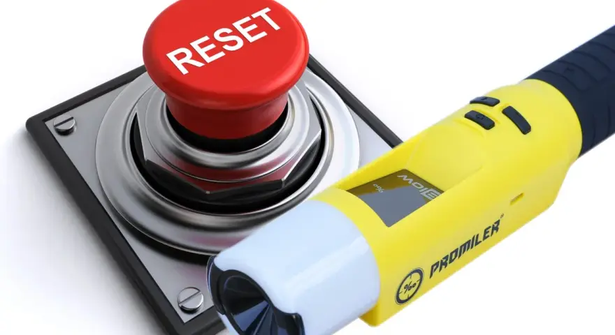 Żółty alkomat Promiler obok czerwonego przycisku RESET.