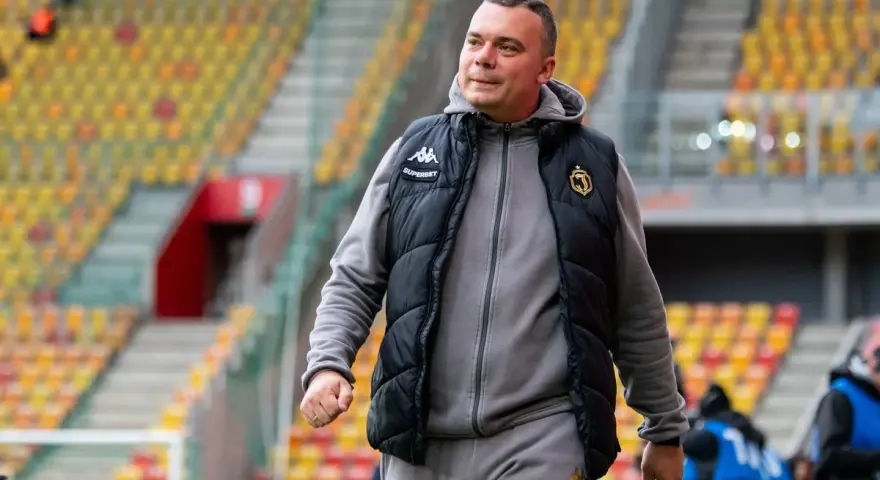 Mężczyzna w kamizelce Jagiellonii, być może omawia nowe jagiellonia transfery na tle pustych trybun stadionu.