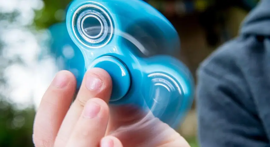 En blå finger spinner snurrar snabbt i handen, med suddiga kanter som visar rörelsen.