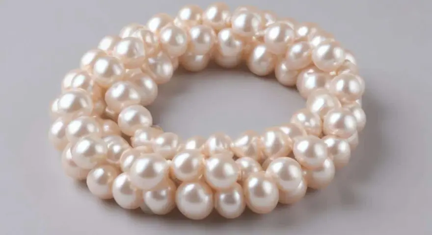 Collana di perle d'acqua dolce, simbolo di purezza e saggezza. Le perle sono disposte in un cerchio su sfondo grigio.