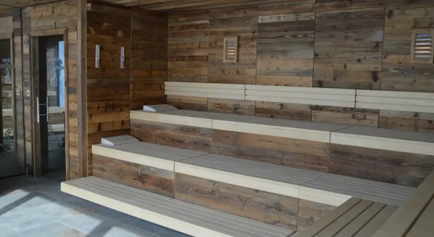 Drewniana sauna w domu z wielopoziomowymi ławami i kamienną podłogą. Idealne miejsce na relaks.