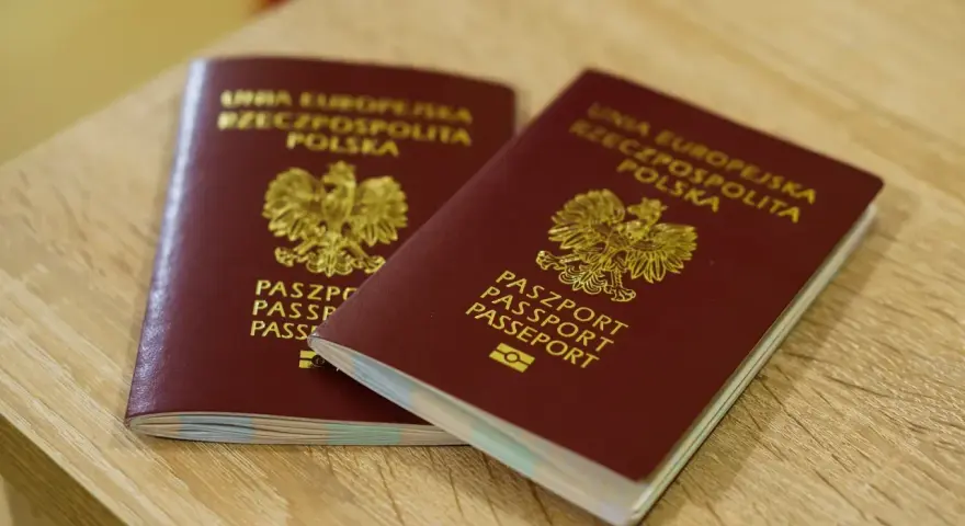 Dwa polskie paszporty leżące na drewnianym blacie.