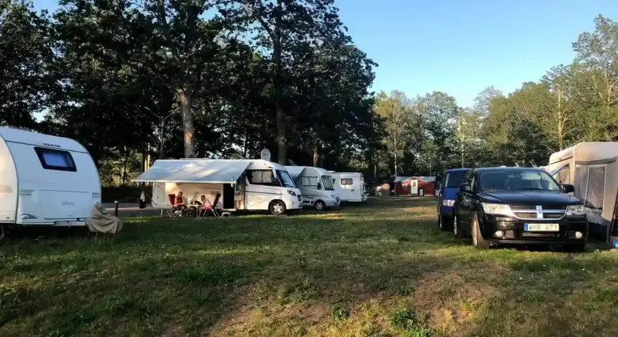 Solig dag på Alsterbro camping med husvagnar, husbilar och bilar uppställda på gräset.