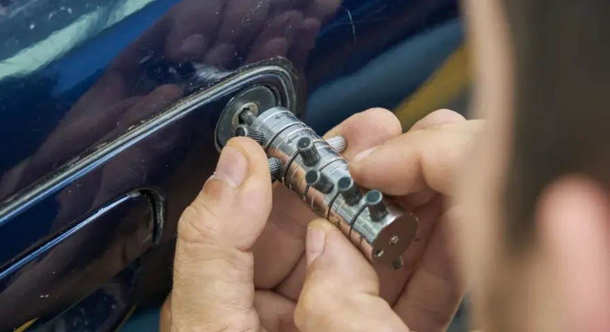 Specjalista manipuluje zamkiem, by otworzyć auto. Dowiedz się, ile kosztuje awaryjne otwieranie samochodu.