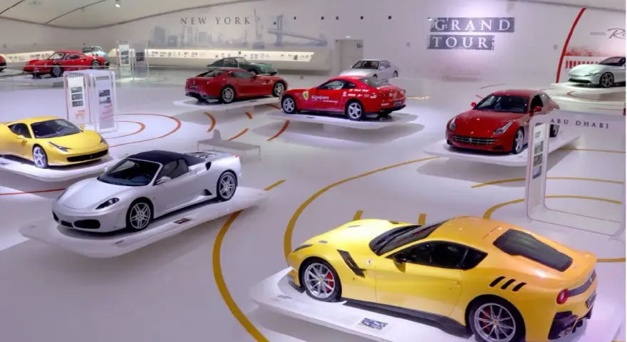 W muzeum Ferrari w Maranello lub w Modenie, na wystawie "Grand Tour", prezentowane są lśniące modele, w tym żółty i srebrny kabriolet.