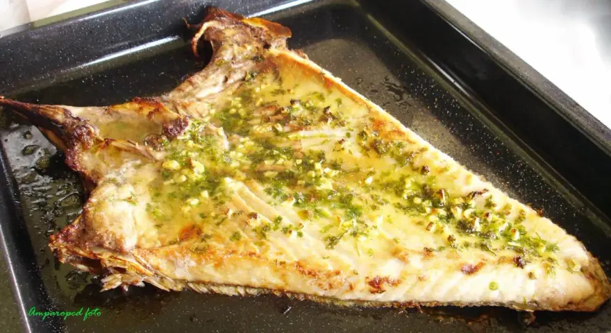 Deliciosa ventresca al horno, dorada y jugosa, con un aderezo de ajo y perejil que invita a probarla.