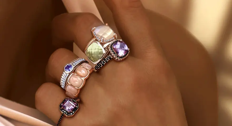 Dita adornate con anelli che esaltano il loro fascino, un vero **materiale prezioso** che cattura la luce.