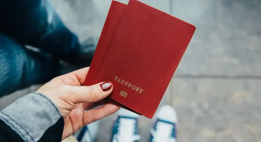 Dłoń trzyma paszport. Zastanawiasz się, ile kosztuje zmiana nazwiska? Czas na podróż i nowe życie!
