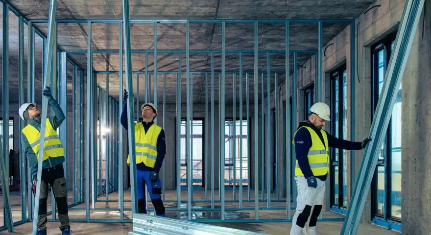 Budowlańcy montują konstrukcję ścian z profili UA. Praca na budowie postępuje.