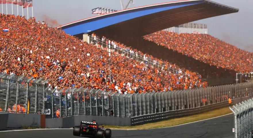 Un coche de Fórmula 1 compite en el Dutch Grand Prix ante una multitud masiva vestida de naranja.
