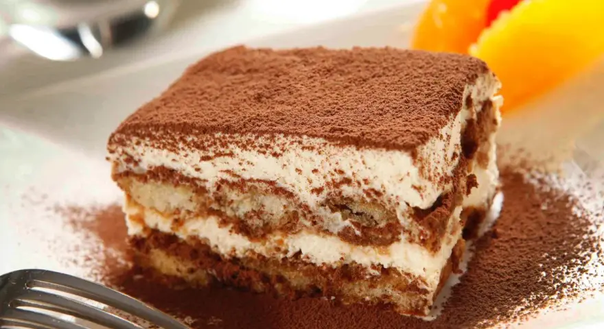 Pyszne tiramisu Ani Starmach, posypane kakao, z owocami i wisienką. Idealne na deser.