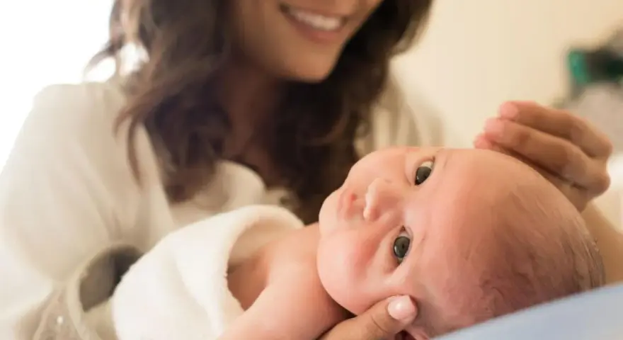 Lächelnde Mutter hält ihr Baby, das gerade einen Wachstumsschub durchmacht.