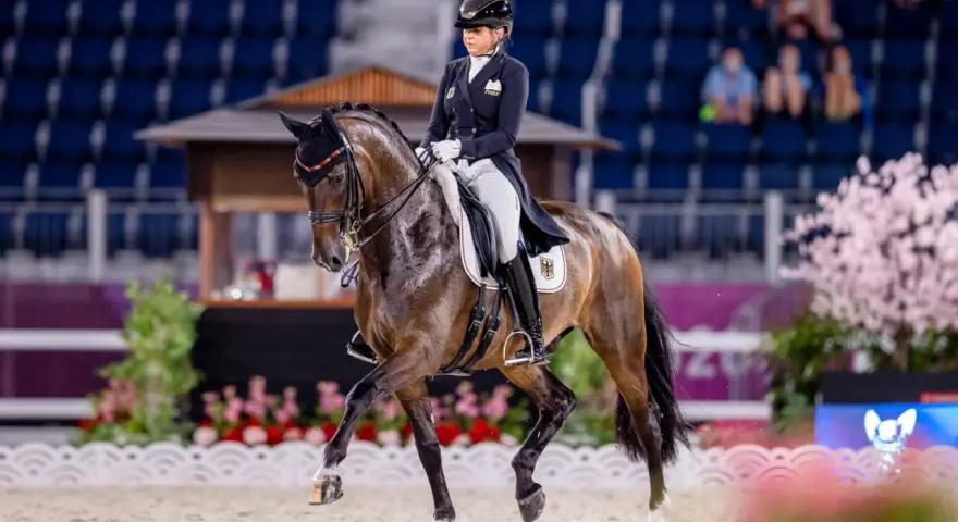 Une cavalière en tenue d'apparat, Sandro Hit, exécute une figure de dressage devant un public.