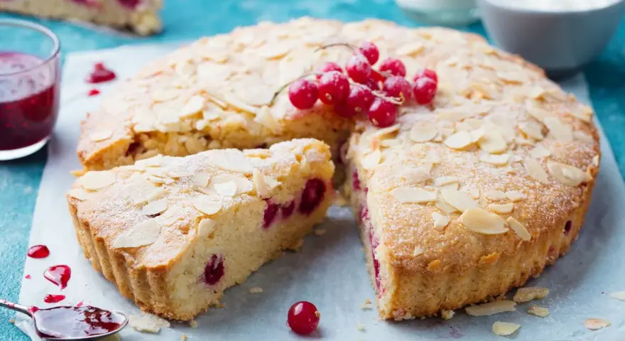 Saftiger zitronenkuchen ohne mehl, mit roten Johannisbeeren und Mandelblättchen bestreut. Ein Genuss!