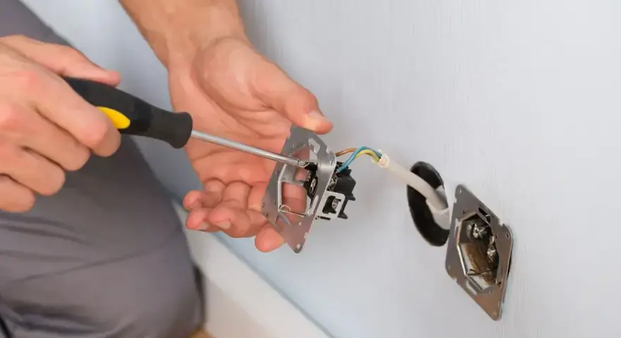 Elektryk montuje gniazdko, co może być związane z problemem braku uziemienia w domu.