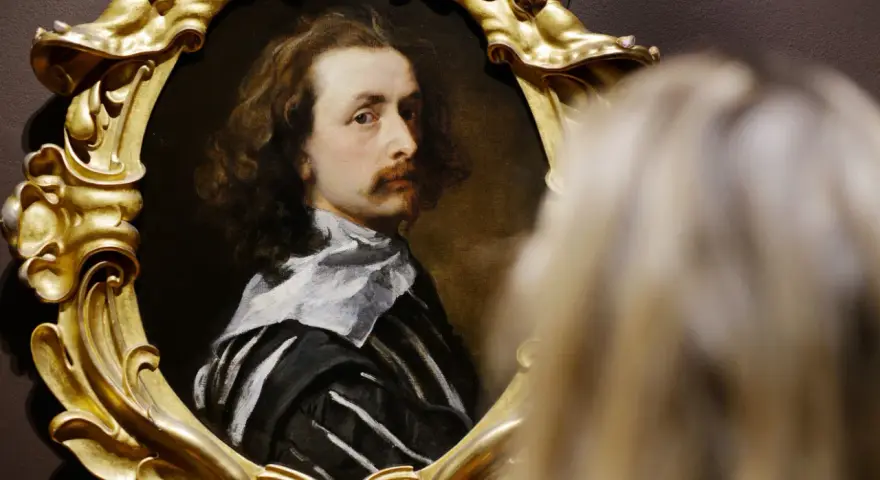 Portret mężczyzny w złotej ramie, jedno z dzieł Antoona van Dycka, oglądany przez widza.