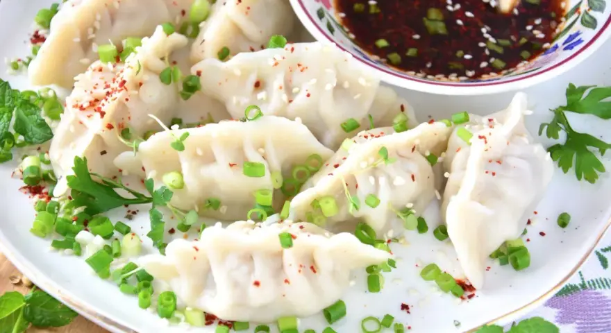 Pyszne pierożki gyoza, posypane szczypiorkiem i sezamem, gotowe do podania z sosem. Idealny przepis na domowe gyoza!