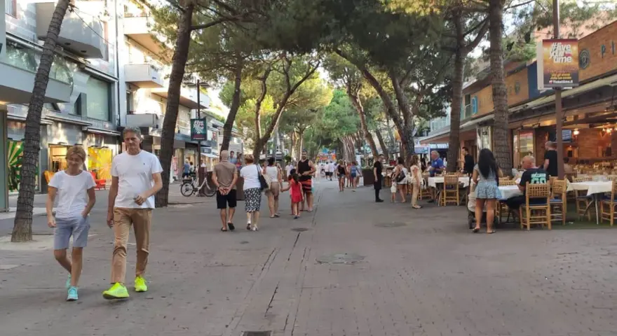 Passeggiata serale nel riccione centro storico, tra negozi e ristoranti all'aperto sotto gli alberi.