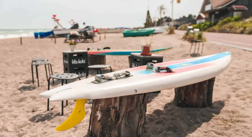 Windsurfbrett am Strand, ein echter Dahme Geheimtipp für Wassersportler. Gelbe Finne ragt aus dem Sand.