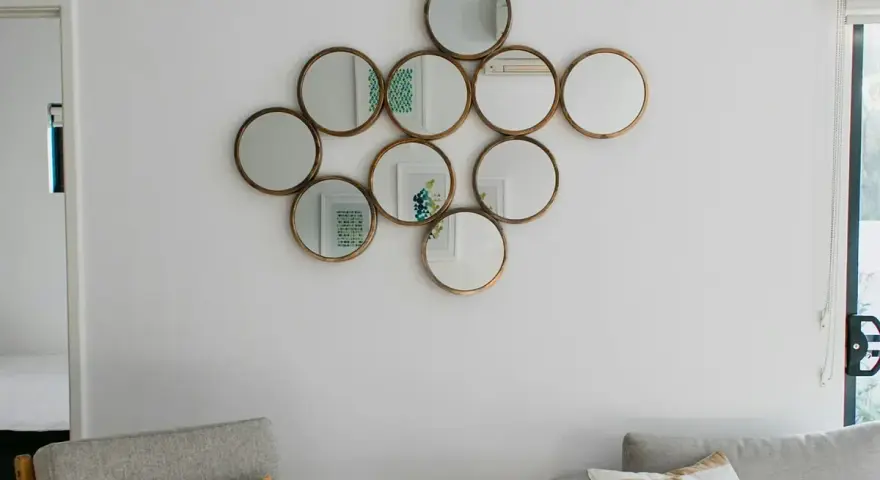 Un conjunto de espejos redondos dorados, dispuestos como una constelación, es una excelente idea de qué poner en una pared vacía.