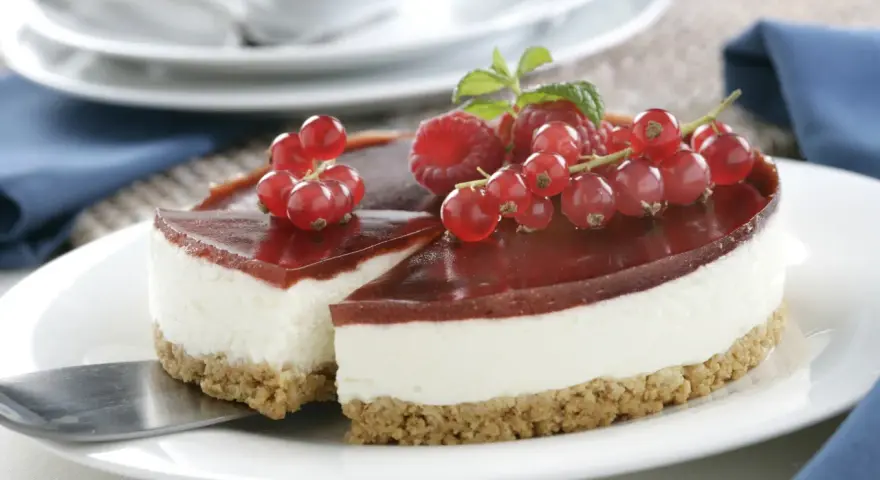 Tarta de queso Philadelphia con frutos rojos y gelatina de fresa, lista para servir.