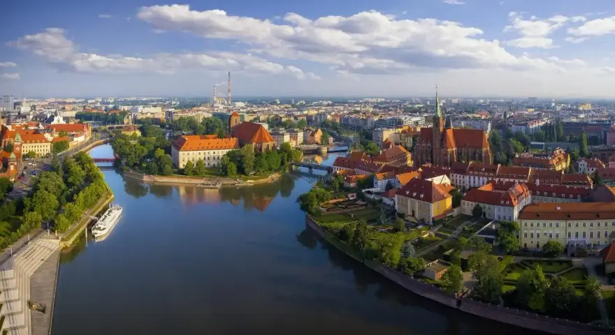 Majówka we Wrocławiu: malowniczy widok na Ostrów Tumski z rzeką i zabytkowymi budynkami.