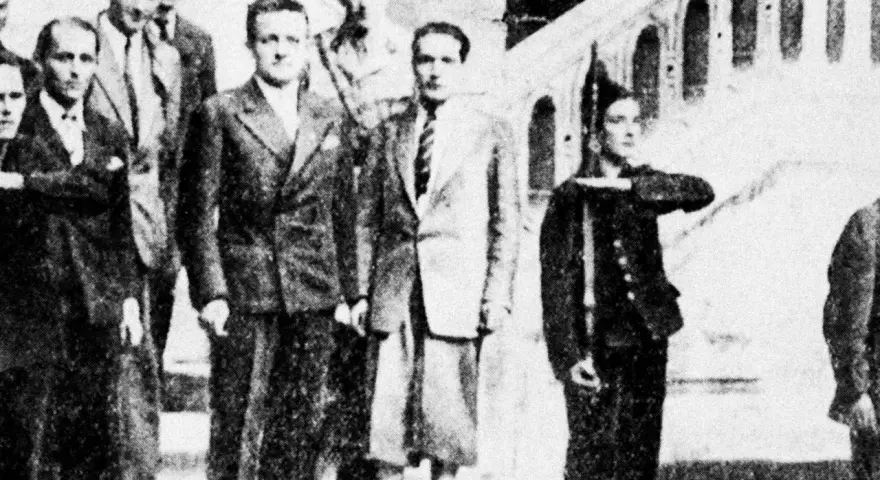 Groupe d'hommes en costume, dont Henri Frenay et François Mitterrand, posant devant un escalier.
