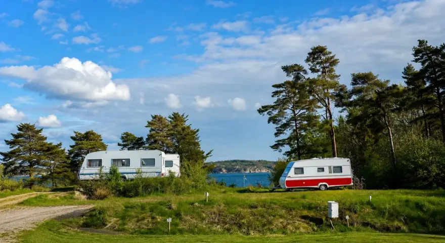 Två husvagnar på en grönskande campingplats vid havet i Lysekil. Blå himmel med vita moln.