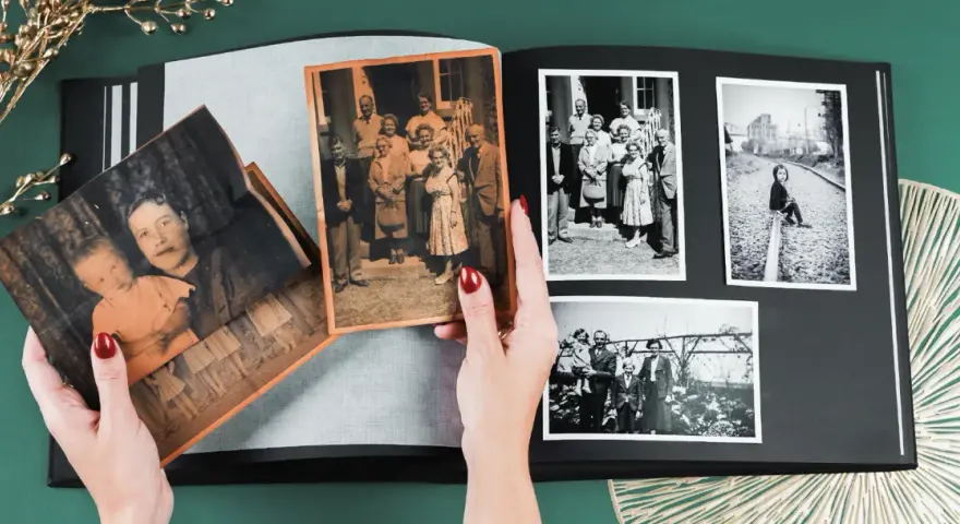Ręce układają stare fotografie w albumie, pokazując, jak skanować zdjęcia i zachować wspomnienia.
