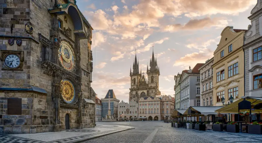 Praga co zobaczyć w jeden dzień: Ratusz Staromiejski z zegarem astronomicznym i Kościół Marii Panny przed wieżami w blasku porannego słońca.