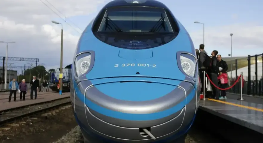 Pendolino Kraków Gdańsk cena: nowoczesny pociąg na torach, pasażerowie czekają na peronie.
