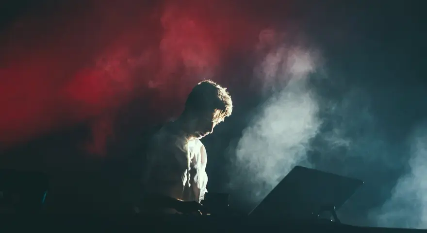 Un DJ dans la fumée rouge et blanche, plongé dans sa musique. Combien de temps avant le traumatisme sonore ?