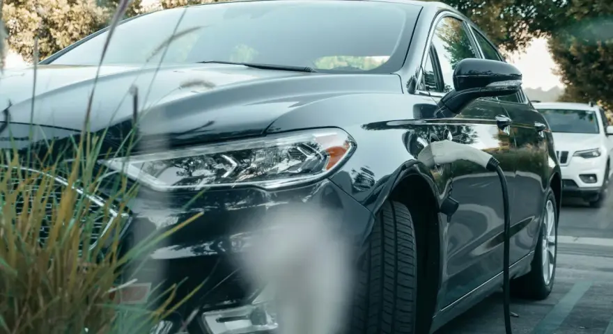 Ciemna toyota hybryda podłączona do ładowarki, gotowa na ekologiczną podróż.
