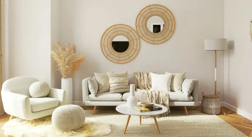 Przytulny salon w stylu scandi chic: jasna sofa, fotel, okrągłe lustra z plecionki, dywan i dekoracje z trawy pampasowej.